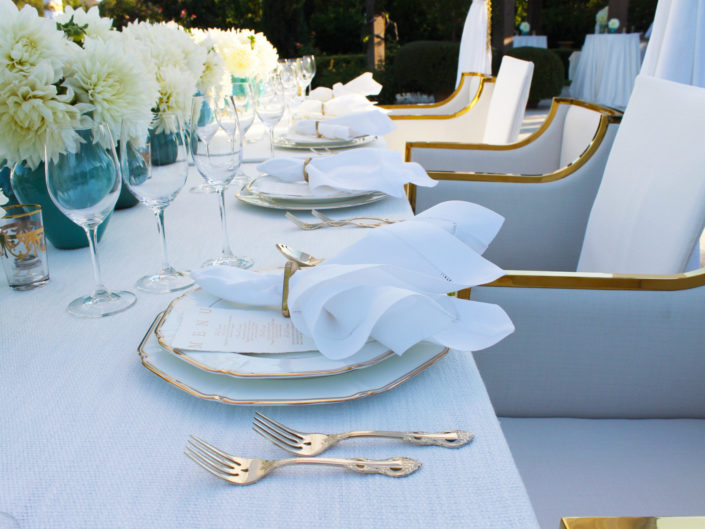 private event, ojai weekend celebration, dinner party, gold rimmed china, gold flatware, wine tasting, gold and white chairs, custom napkins, blue case, teal vase, event florals, gold accents, poolside dinner, event planner in LA, destination event planner, kristin banta